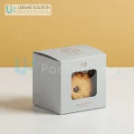 Small cookie gift boxes with clear windows. They display freshly baked cookies inside.